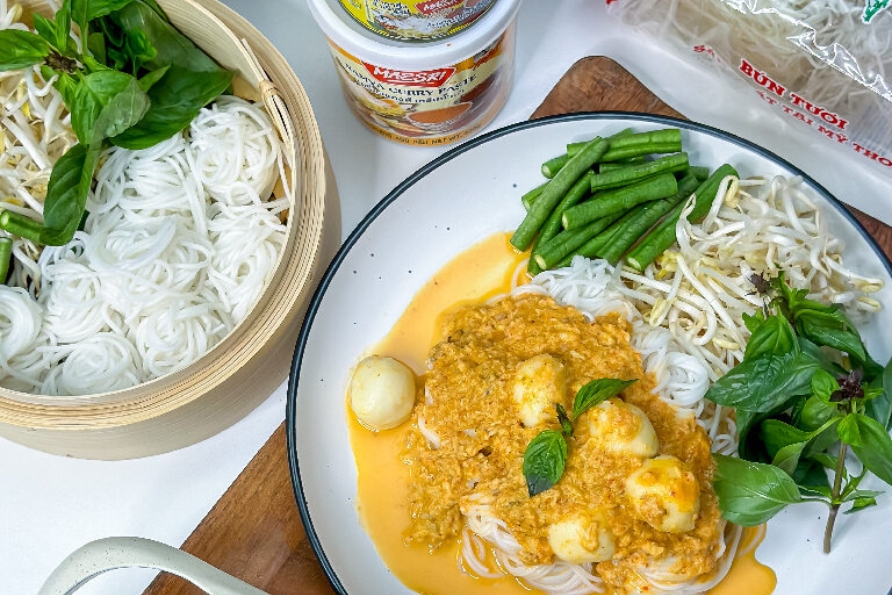 A plate of Kanom Jeen Namya Pla featuring noodles, rice, and vegetables, accompanied by a maesri namya thai noodle sauce.